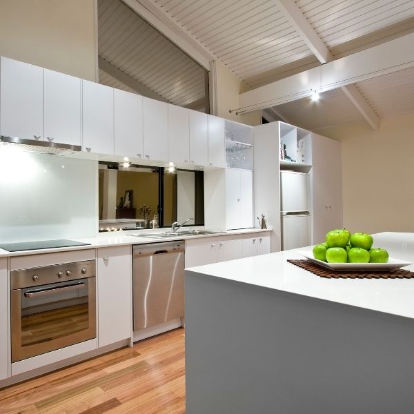 clean modern white kitchen with green apples on counter in bowl