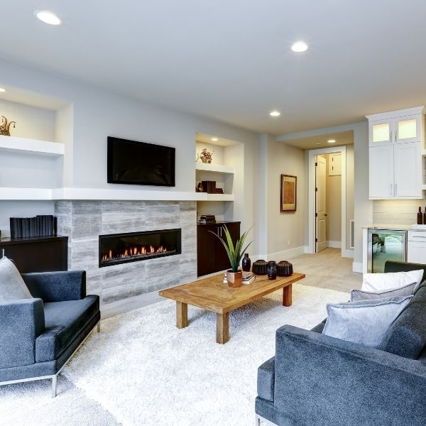 clean living room with blue fabric couches and electric fireplace